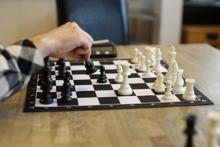 En hånd som flytter en sjakkbrikke på et sjakkbrett