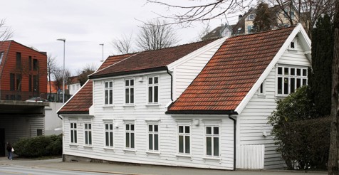 Bildet viser Huset fra utside, et gammelt hvitt trehus i Sveistserstil.
