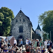Domkirken i sommersol med masse folk foran inngangspartiet.