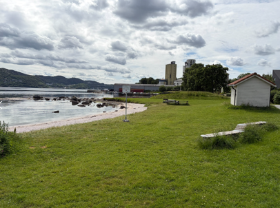 Skilt på Forusstranda. Mølla og siloen i Sandnes i bakgrunnen.