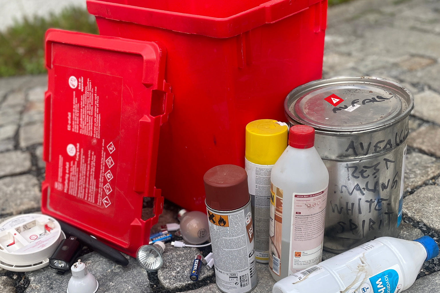 Malingrester, lyspære, batterier og annet farlig avfall foran rød plastboks.
